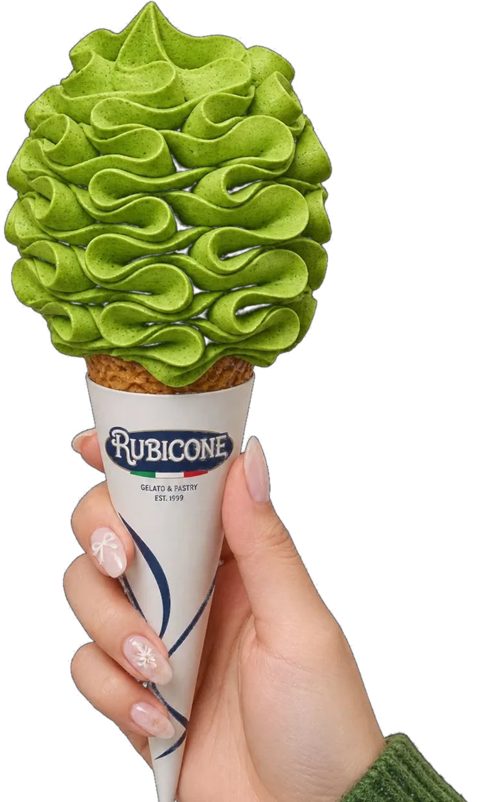 Hand holding a Rubicone cone piped with vibrant green matcha soft serve